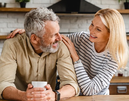 Man and woman leaning on kitchen counter smiling at each other