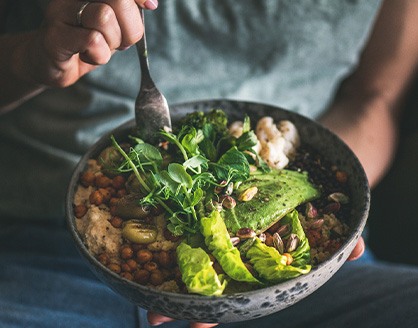 Someone forking healthy salad from bowl in their lap