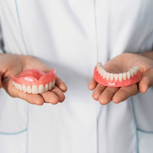 Someone holding palms in front of midsection with dentures on them