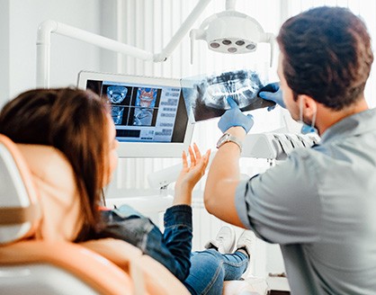 Dentist showing X-rays to patient in dental chair