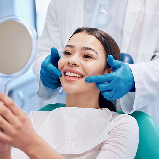 a patient checking her teeth with a mirror