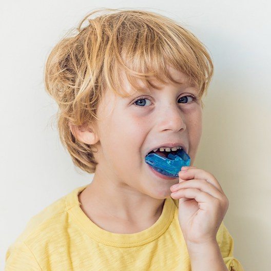 Young boy placing blue athletic mouthguard