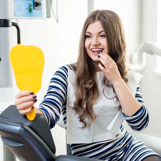 Woman looking at her smile in a mirror.