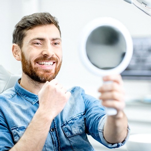 man admiring the results of his dental bonding in a mirror