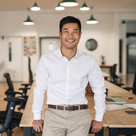 a person leaning against a wooden desk in an office