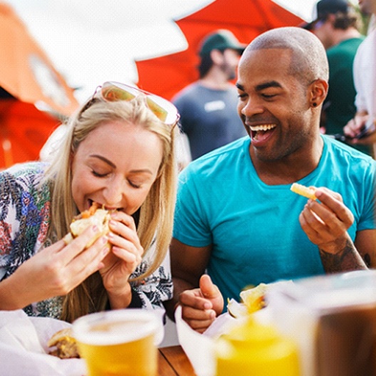 two friends eating food together at a festival