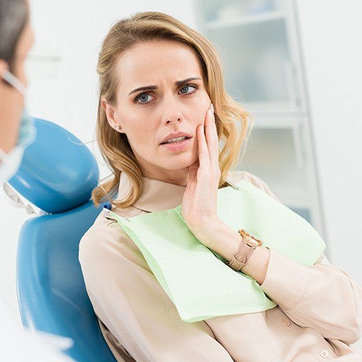 Woman in need of tooth extraction holding cheek