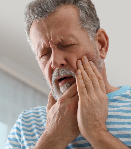 Man in need of emergency dentistry holding cheek