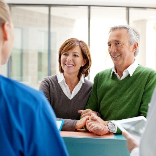 Man and woman checking in at dental office reception desk