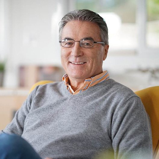 Man with glasses sitting in chair and smiling