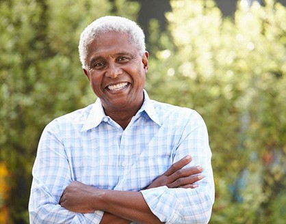 Man standing outside with arms folded and smiling