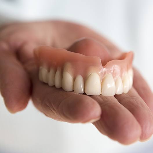 Hand holding full denture