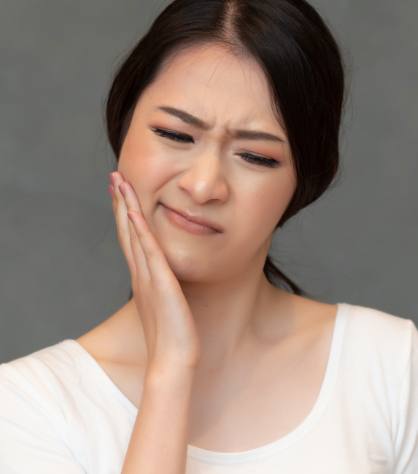 Woman in need of emergency dentistry holding cheek