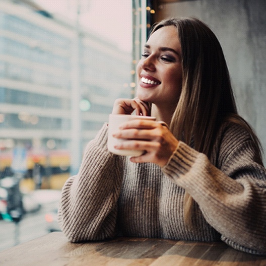 Woman with veneers smiling at city coffee shop