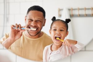 a father and daughter brushing their teeth together