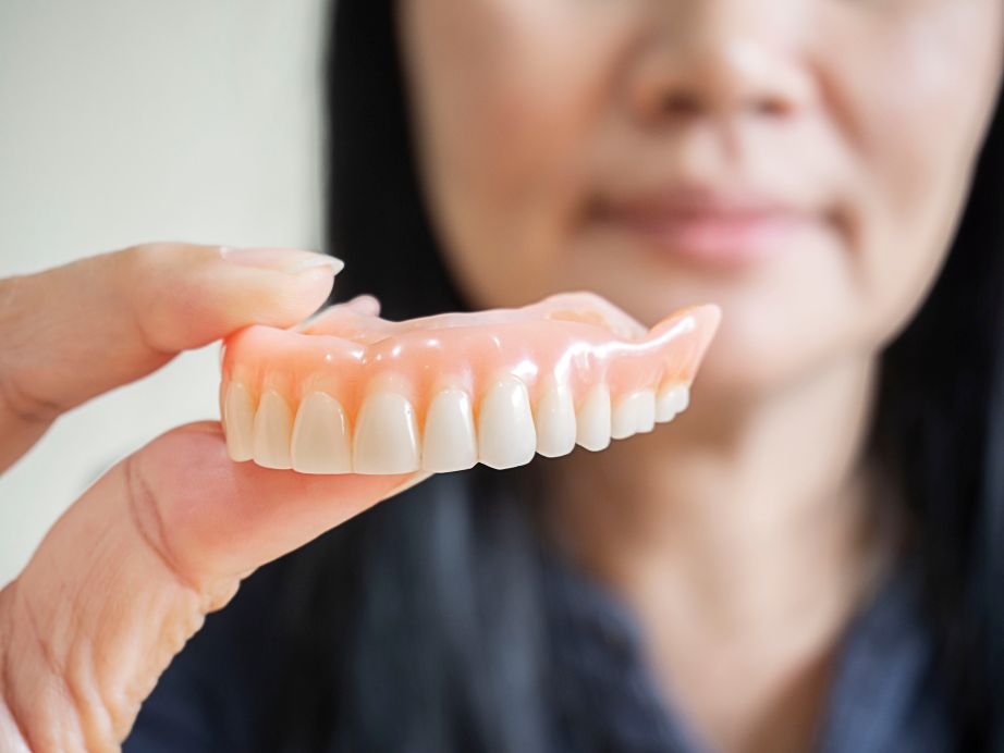 A woman holding an upper-arch denture
